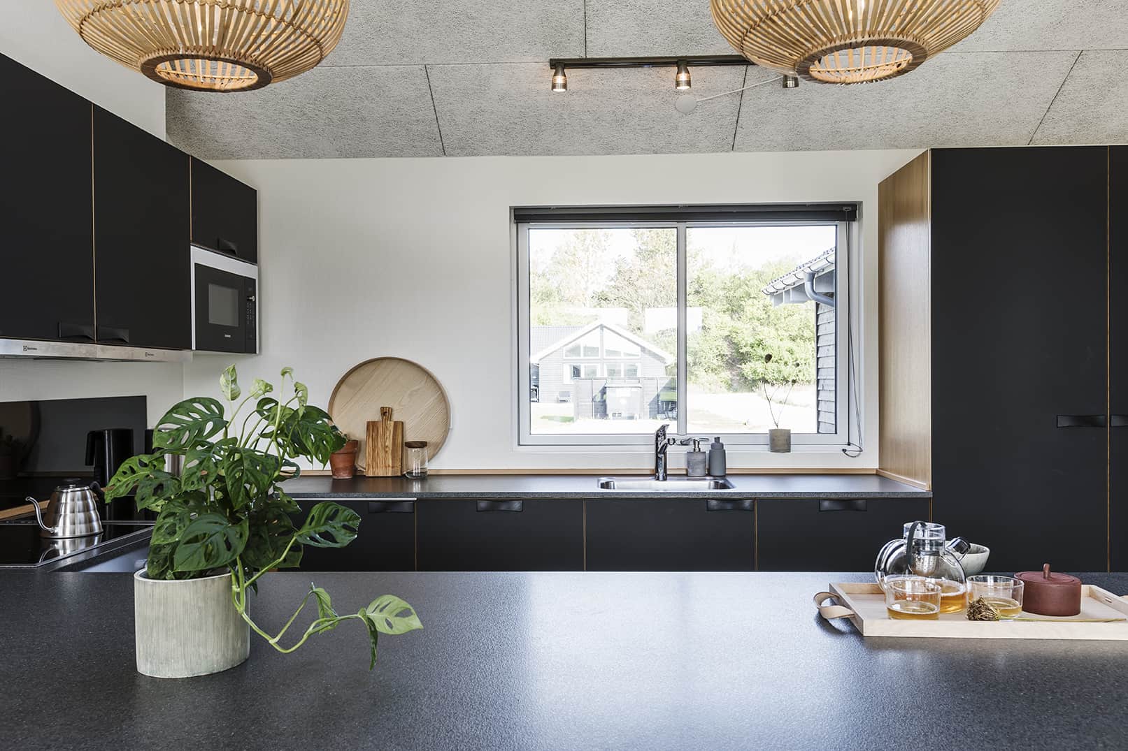 Køkken med mørkt inventar og lyst vindue