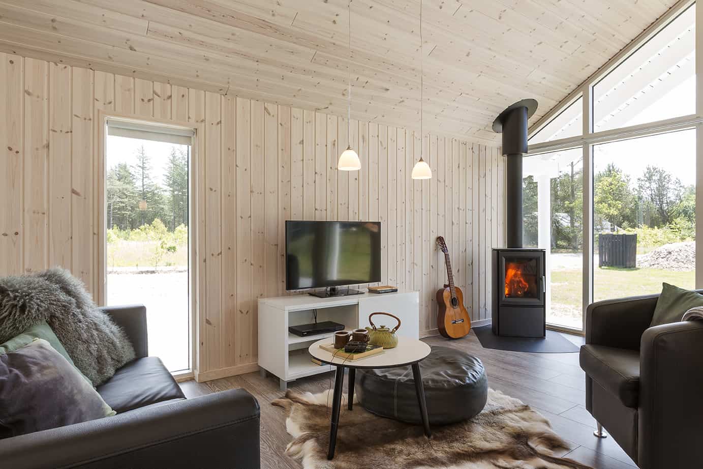 Træbeklædt stue med tv på tvmøbel og brændeovn