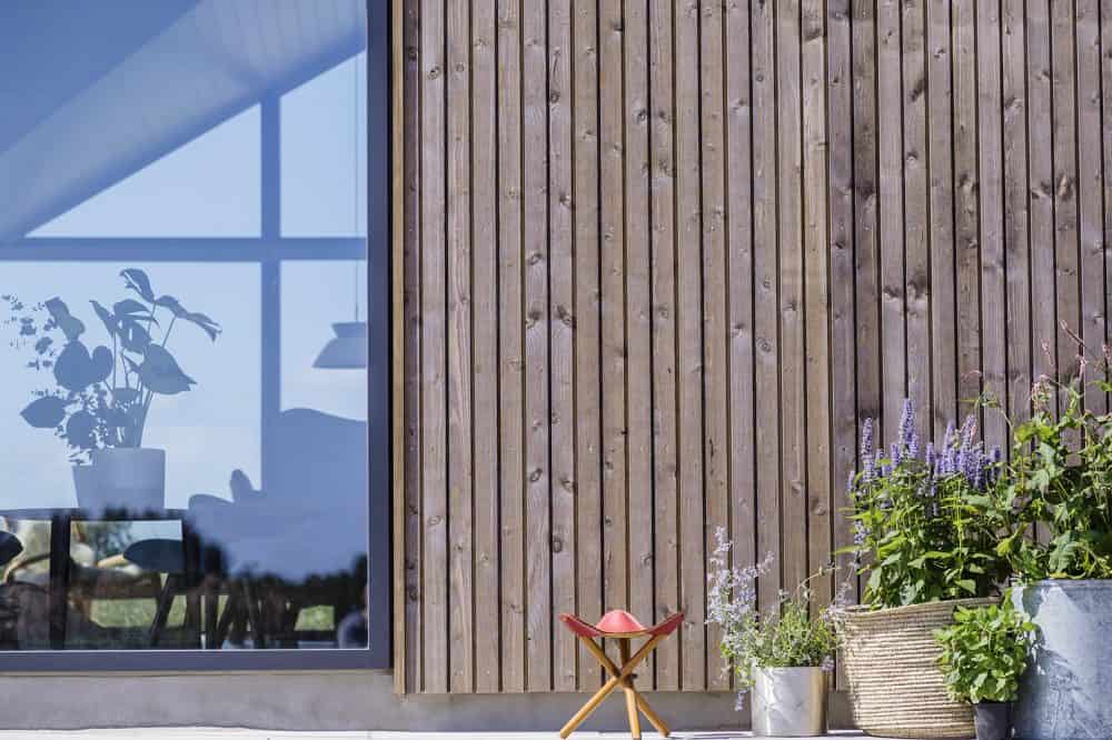 Sommerhus med vinduesparti og udendørs beplantning i krukker