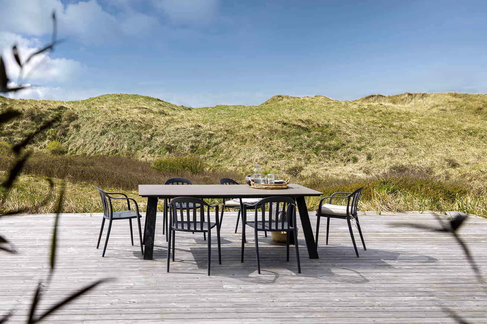 Terrassemøbler på træterrasse med klitter i baggrund