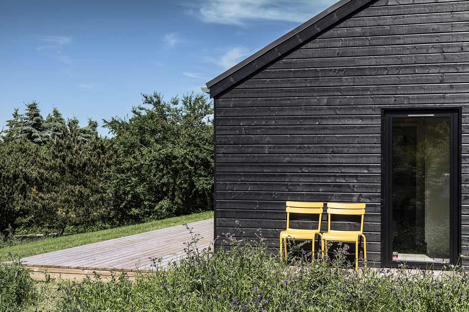 Closeup af sommerhus set udefra med to stole i solskin