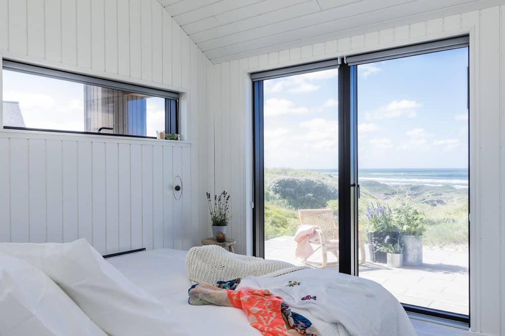 Udsigt gennem store velfac vinduer i soveværelse