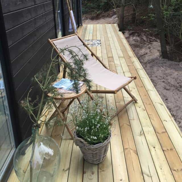 Strandstol på træterrasse med plante og bord