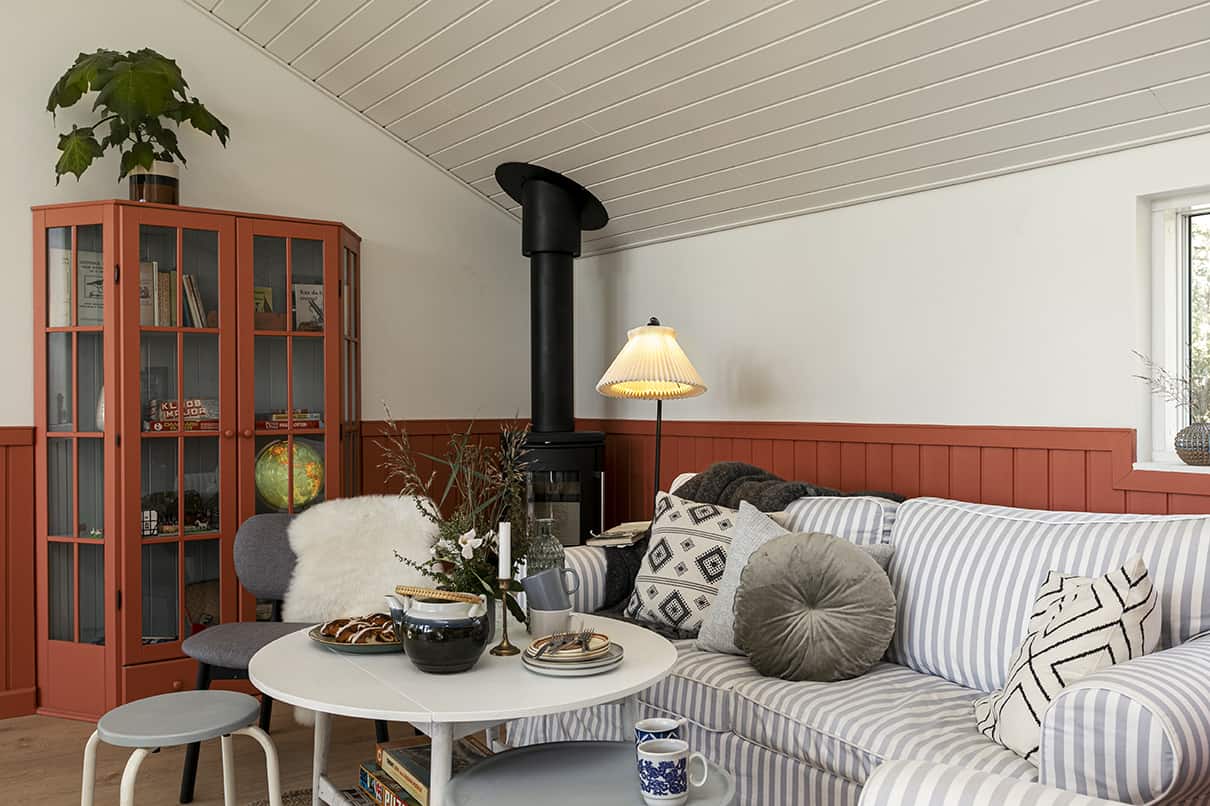 Hyggekrog i sommerhus med sofa og brændeovn