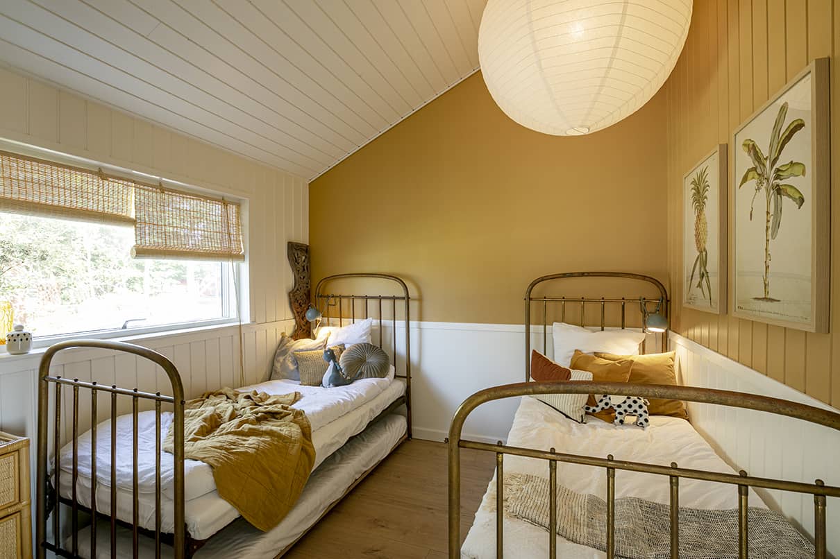 Soveværelse med to enkeltsenge, gul væg og vindue