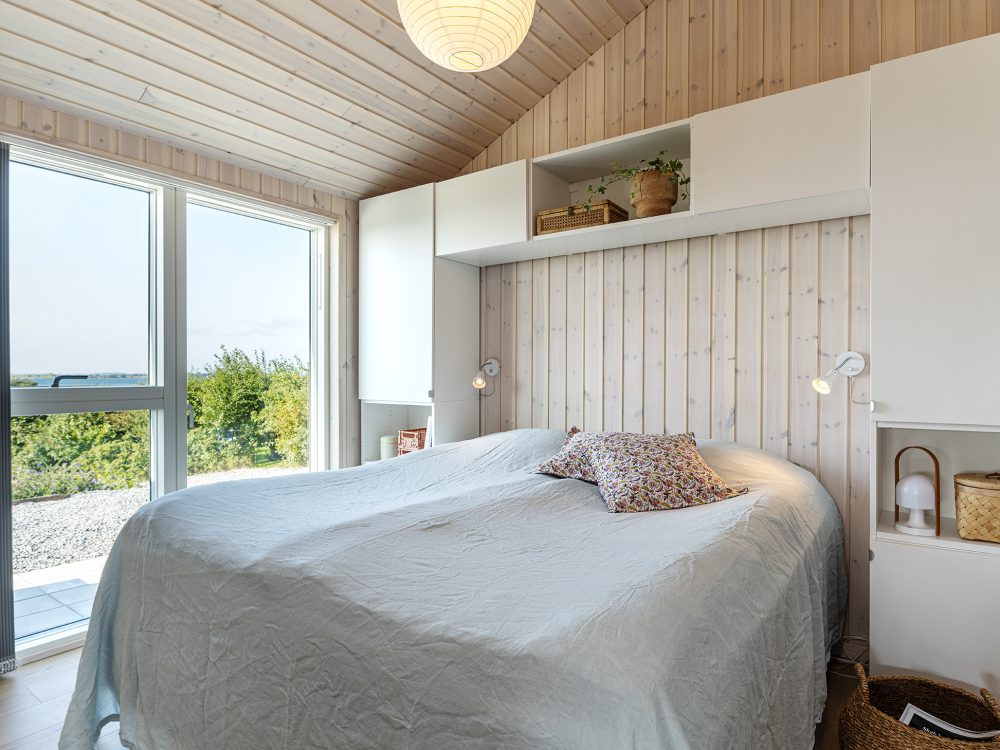 Værelse med dobbeltseng i lyst rum med opbevaring