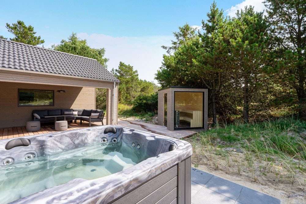 Udendørs spa på terrasse med sauna i baggrund