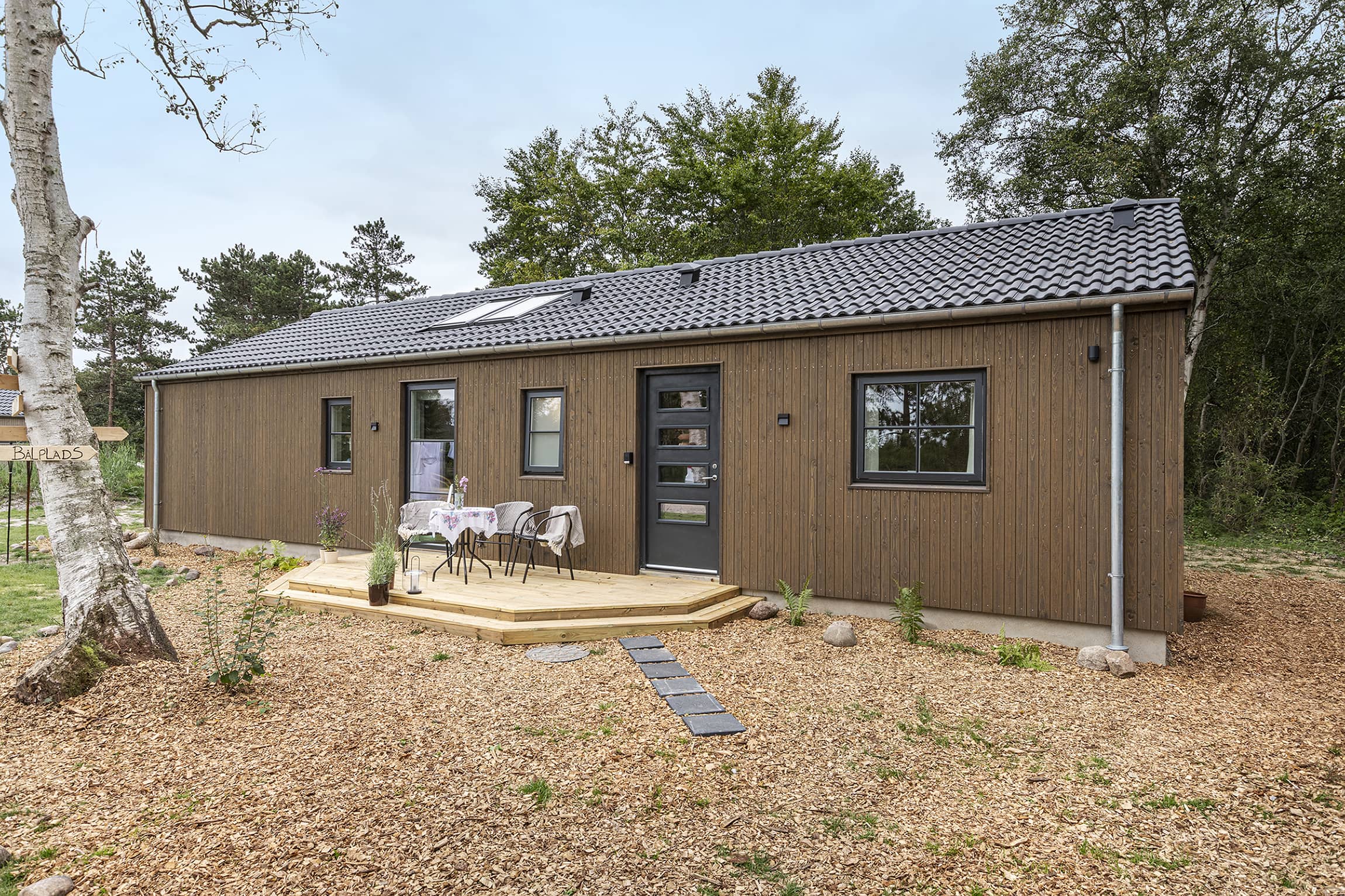 Louise og Nicolajs hyggelige forhave med veranda fra TV2 Sommerdrømme 2022. Trend Basic sommerhus fra Skanlux Byggefirma A/S Skanlux sommerhus