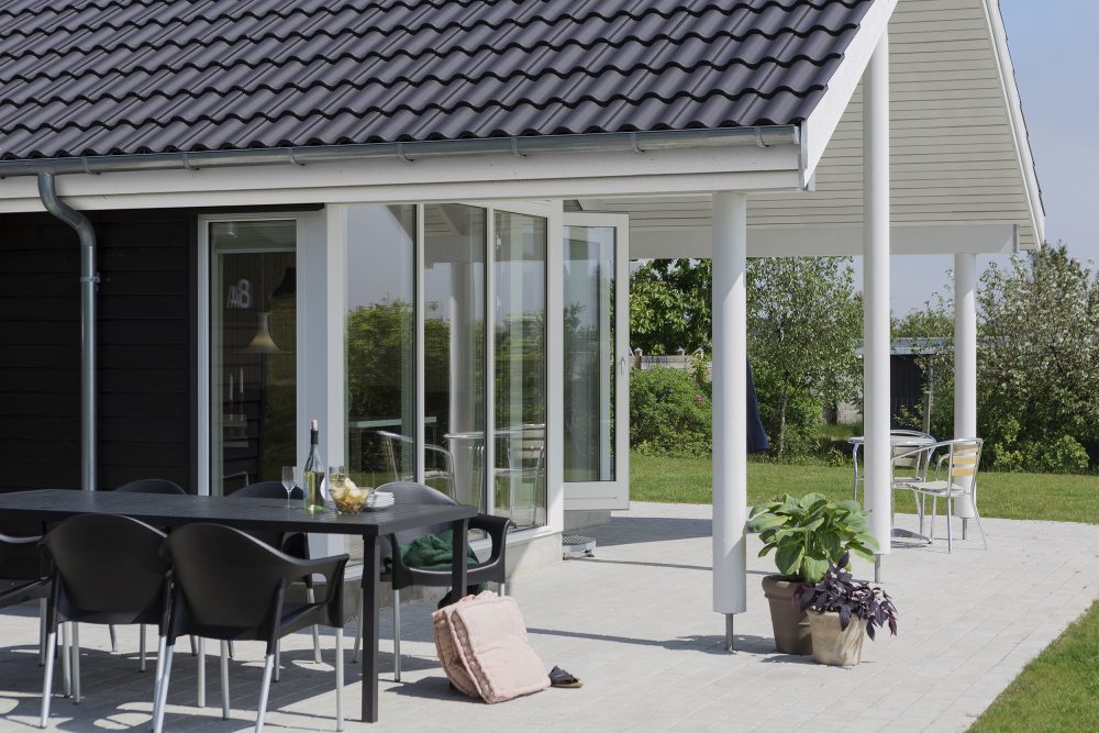 Havemøbler på terrasse med halvtag i baggrunden