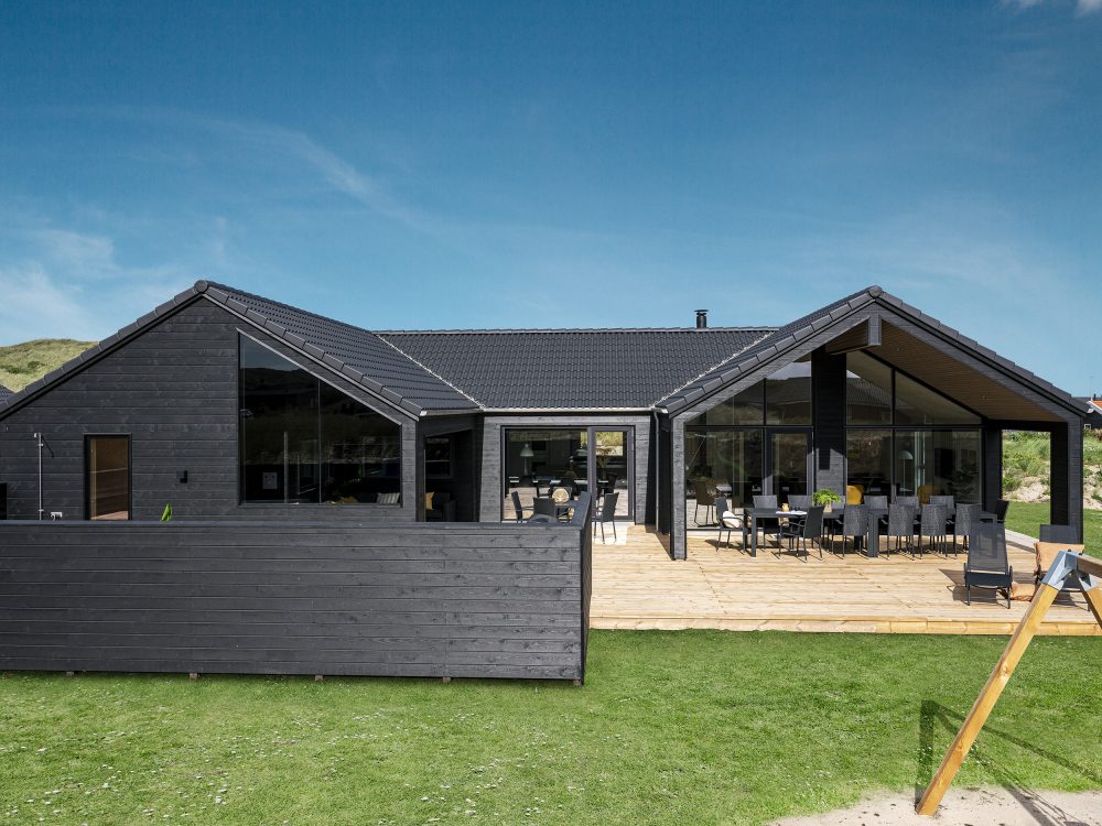 Stort, sort sommerhus set fra haven