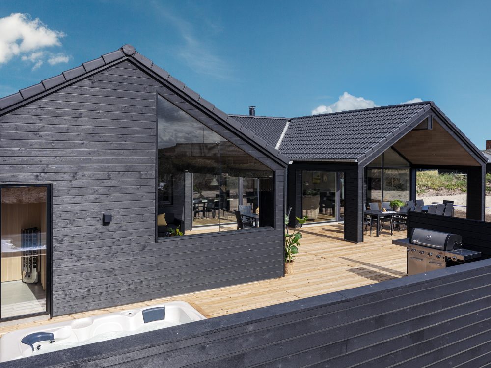 Stort sommerhus med stor træterrasse set udefra