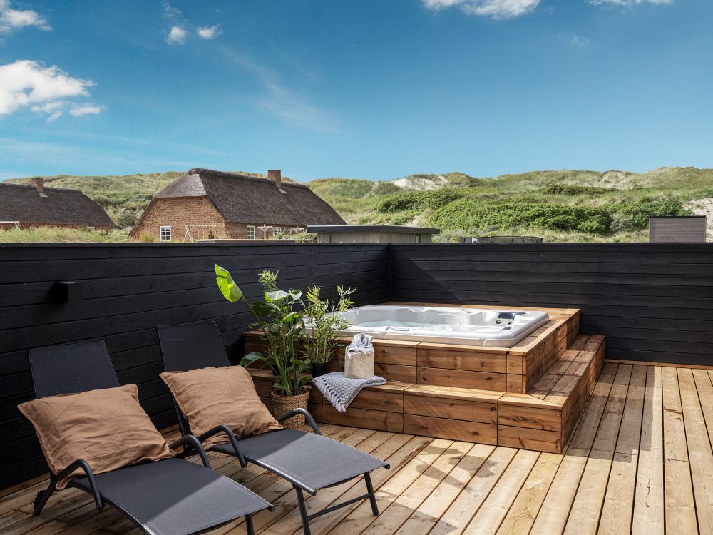 Udendørs pool på træterrasse med klitter i baggrunden