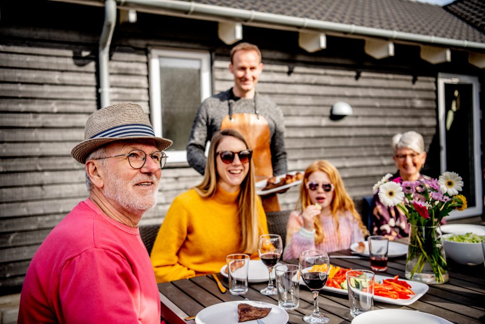 Familie spiser udenfor foran træsommerhus
