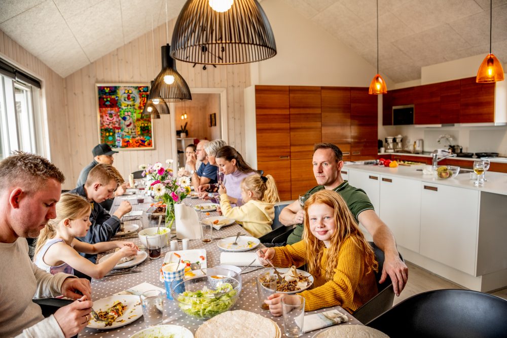 Familie spiser ved køkkenbord i hyggelig belysning