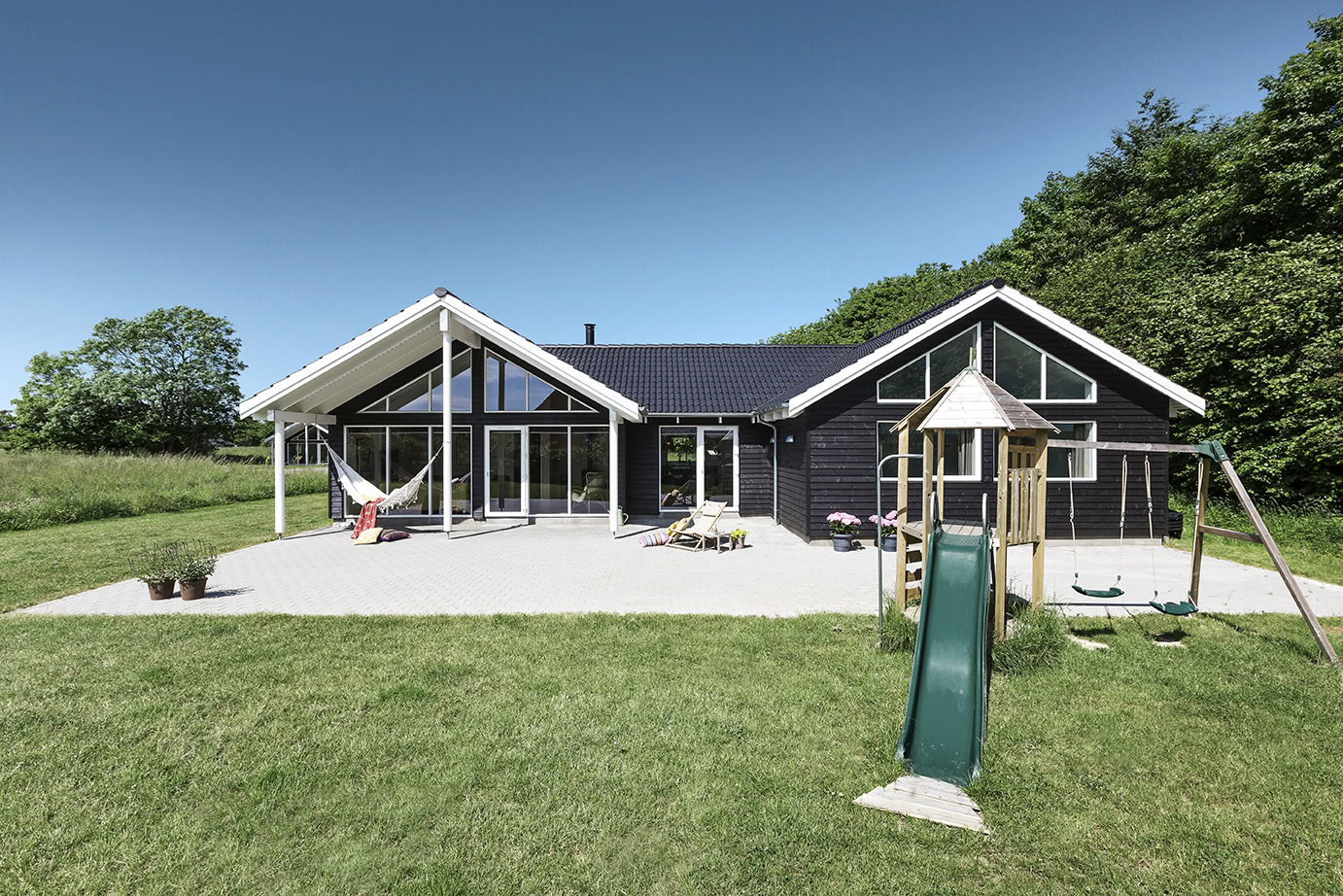 Skanlux sommerhus med legetårn set fra haven