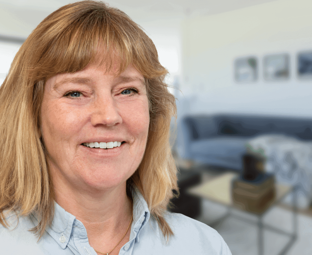 Portrætfoto af Ann Kaae med stue i baggrund