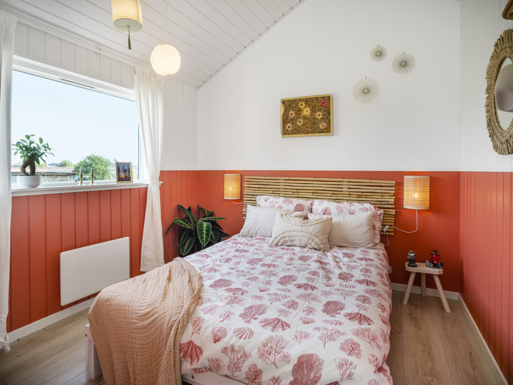 Farverigt sengebetræk og rød trævæg