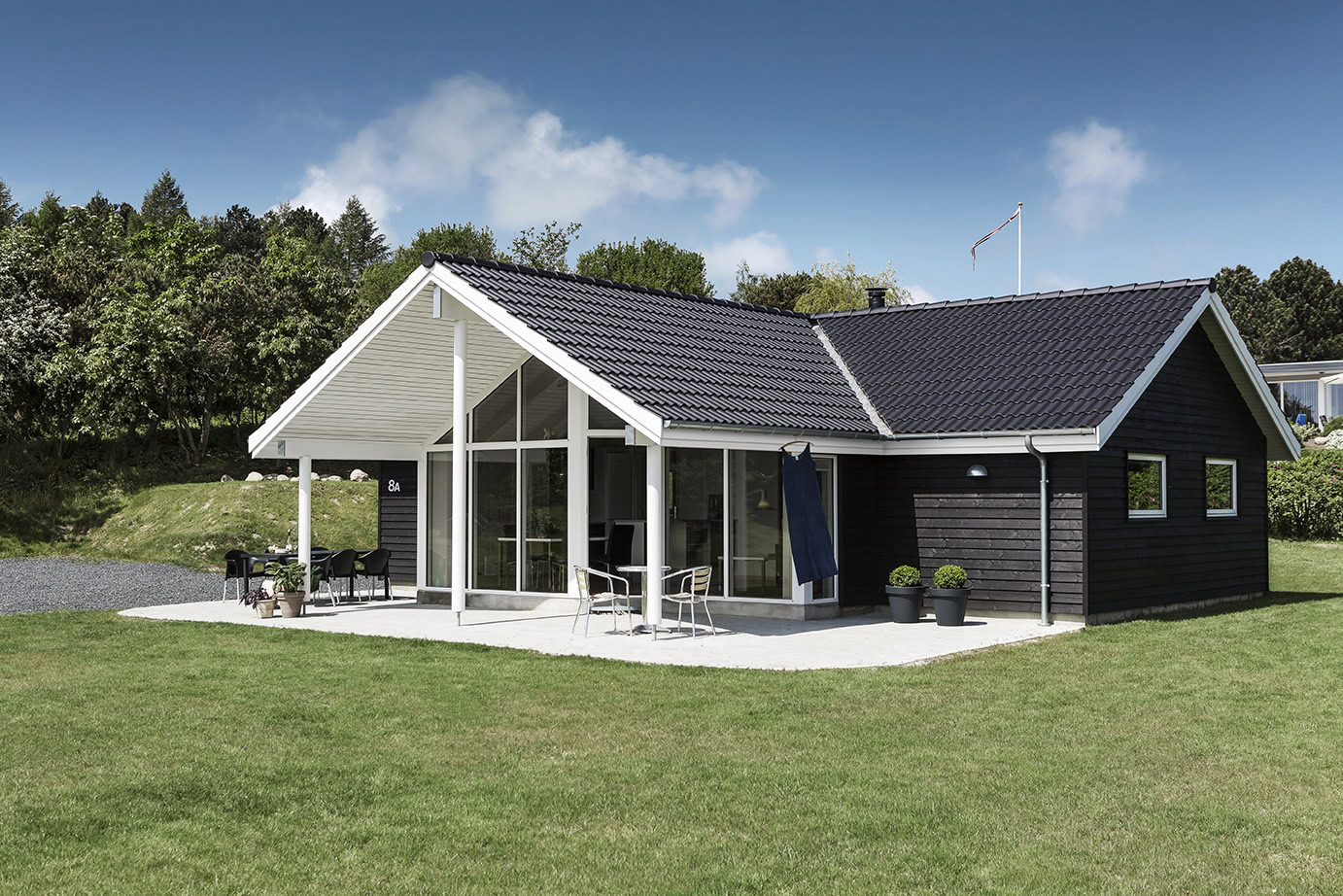 Sommerhus i solskin med grøn græsplæne