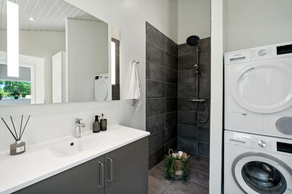 Badeværelse med sorte klinker og vaskesøjle