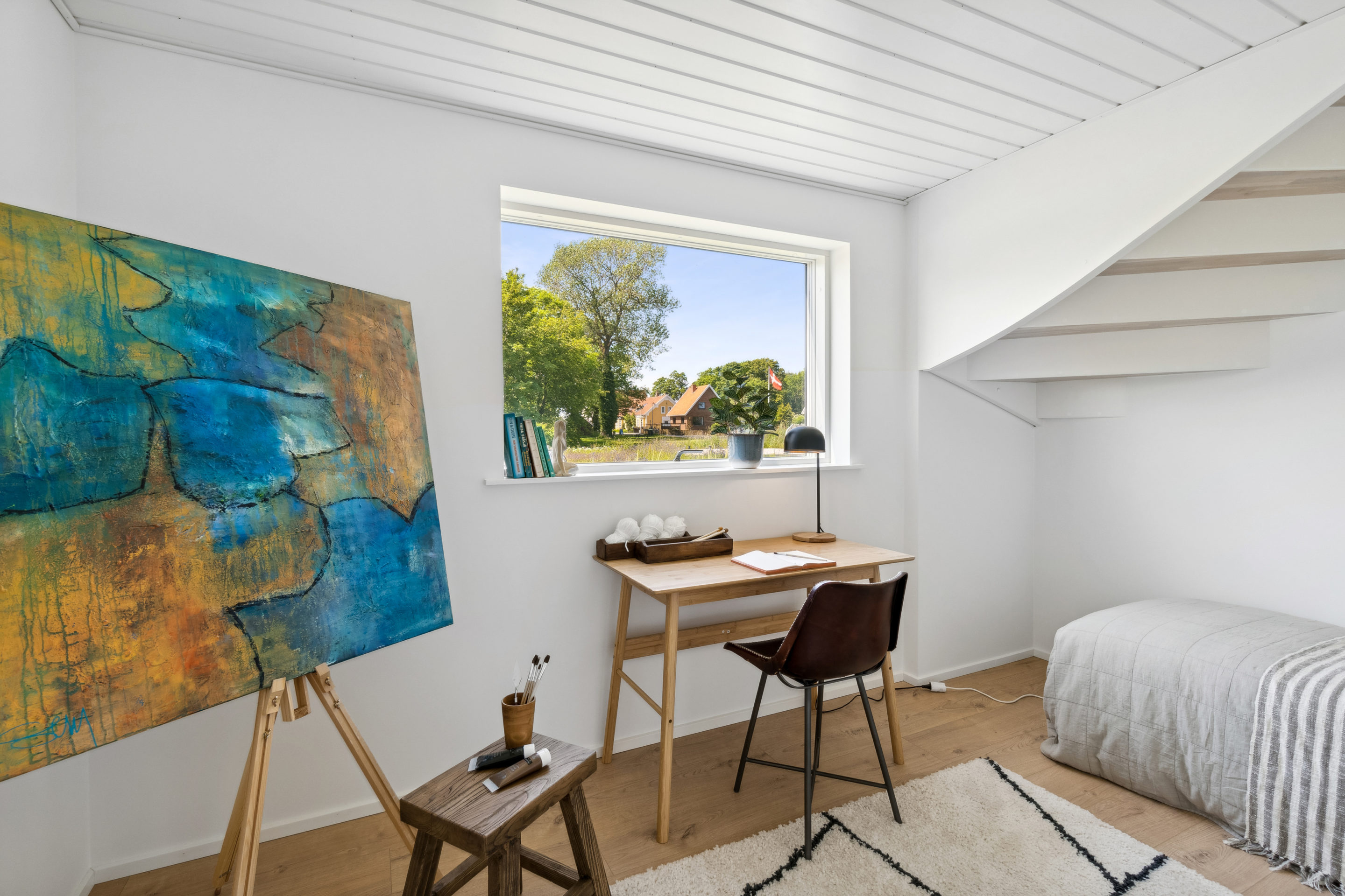 Værelse med maleri og enkeltseng under trappe