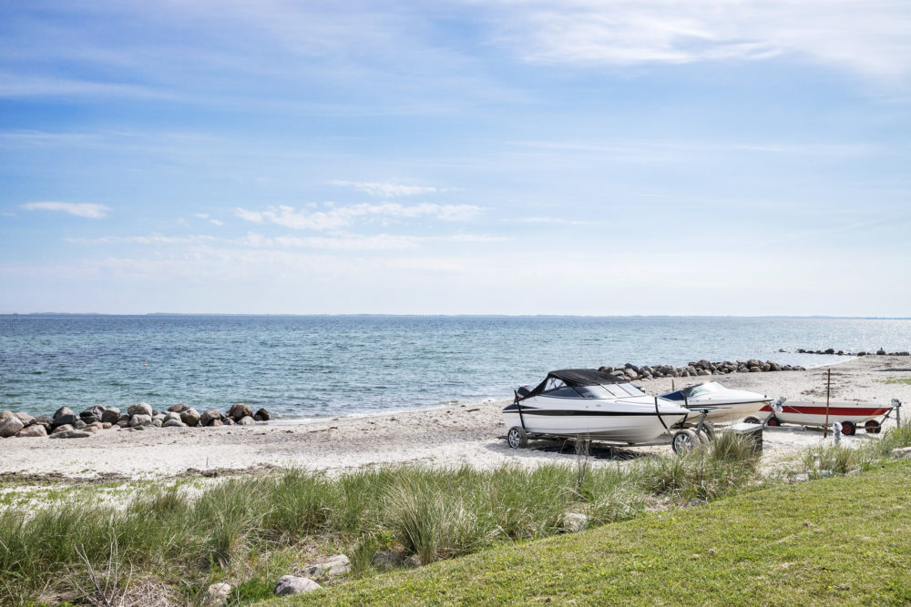 Både liggende i strandsand med vand i baggrunden